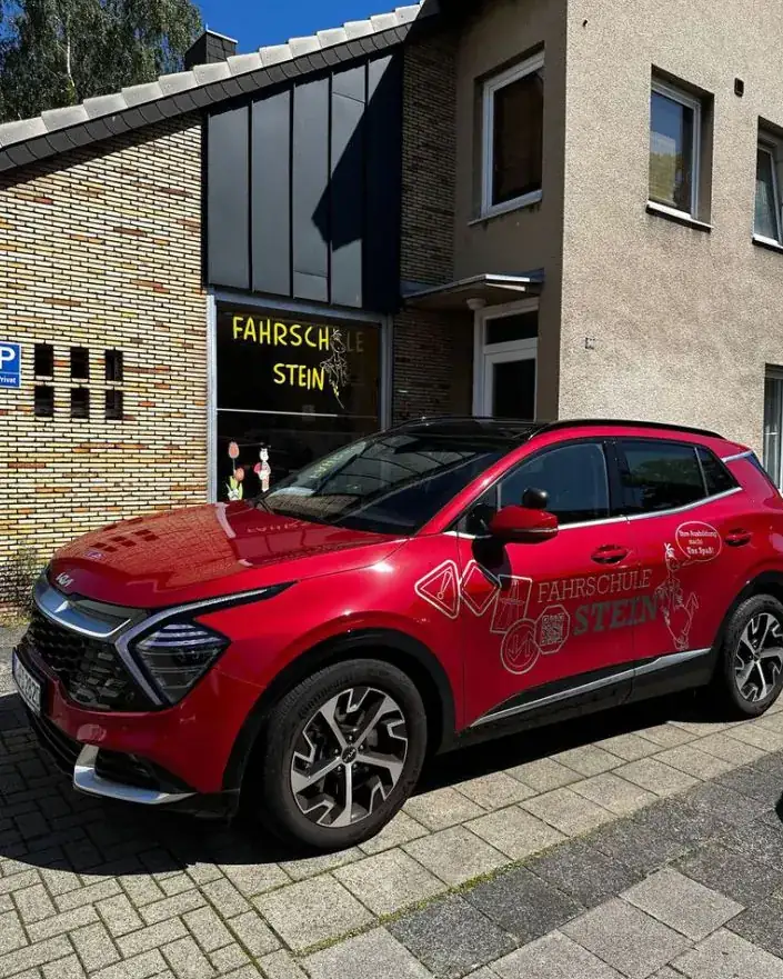 Das rote Fahrschulauto vor dem Laden der Fahrschule Stein an der Kaiserstraße
